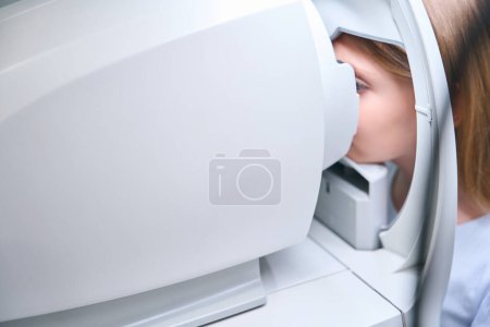 Téléchargez les photos : Gros plan de la petite fille regardant à l'intérieur réfracteur automatisé pendant la procédure de dépistage de la vision - en image libre de droit