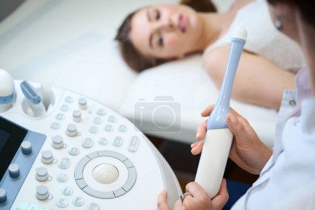 Photo for Ultrasound woman communicates with the patient before an ultrasound of the uterus, the doctor uses special gadgets - Royalty Free Image