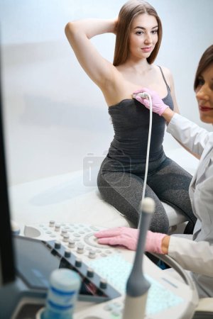 Téléchargez les photos : Jeune femme sur la procédure d'échographie mammaire, uzist féminine travaillant sur un dispositif moderne - en image libre de droit