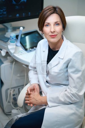 Téléchargez les photos : Femme médecin assis dans une chaise de bureau confortable sur le lieu de travail, le bureau est équipé d'un équipement moderne - en image libre de droit