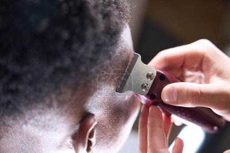 Foto de Peluquería utiliza un cortador moderno en su trabajo, su cliente tiene el pelo rizado - Imagen libre de derechos
