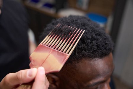 Foto de Peluquería establece el pelo de los clientes afroamericanos, el maestro utiliza un peine especial - Imagen libre de derechos