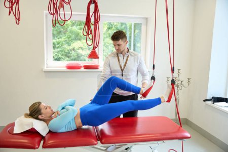 Photo for Pretty client preparing to do suspension therapy with trainer by using redcord indoors - Royalty Free Image