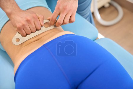 Photo for Registered massage therapist using instrument assisted soft tissue mobilization to make deep muscles and tissues massage to woman client - Royalty Free Image