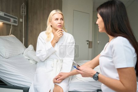 Foto de Dos damas hablando en una habitación de hospital, un médico y un paciente mirando imágenes de ultrasonido - Imagen libre de derechos