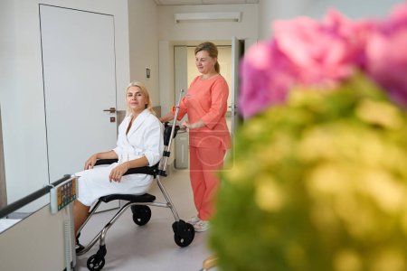 Foto de Un paramédico llevó a una señora a una habitación de hospital en una silla de ruedas, una mujer en una bata de hospital - Imagen libre de derechos