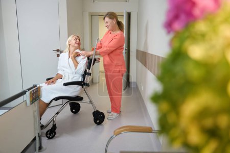 Foto de Un buen paramédico llevó a una señora a una habitación de hospital en silla de ruedas, una mujer en bata de hospital - Imagen libre de derechos