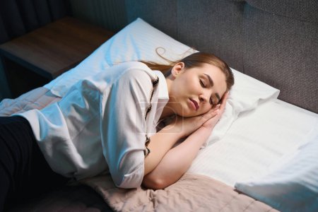 Foto de Vista superior de la mujer caucásica en ropa de lujo con los ojos cerrados acostado en la cama en el hotel - Imagen libre de derechos