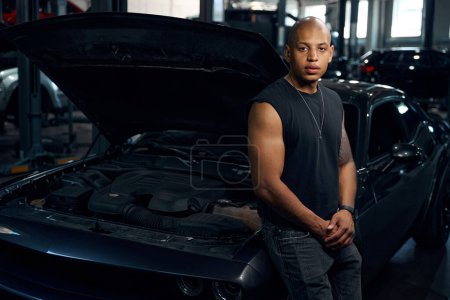 Photo for African American man leaning on car with opened hood, going to repair the motor or diagnosing electric system at service station - Royalty Free Image