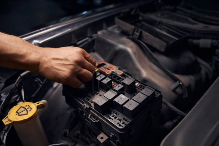 Photo for Male auto-mechanic changing relay and checking operation of the fuses, replacing fuses and controlling car electronics, close-up hands of auto service station worker - Royalty Free Image