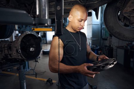 Photo for Concentrated auto-mechanic looking at clutch disc searching for problems, going to repair and maintain vehicle transmission, automobile repair shop - Royalty Free Image