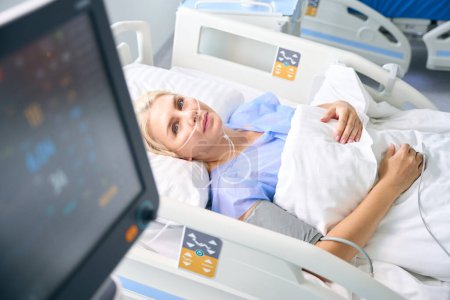 Téléchargez les photos : Femme après la chirurgie se trouve dans une pièce avec un équipement moderne pour surveiller les fonctions vitales des patients - en image libre de droit