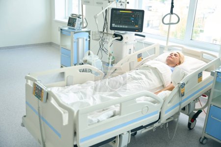 Foto de Paciente se encuentra en una cama especial en una sala con equipos modernos para el seguimiento de las funciones vitales de los pacientes - Imagen libre de derechos