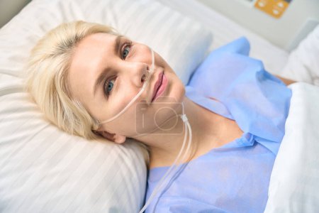 Foto de Linda mujer de ojos azules está conectado a una máquina de oxígeno, equipo médico moderno se utiliza en el hospital - Imagen libre de derechos