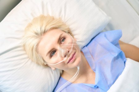 Téléchargez les photos : Belle femme aux yeux bleus est connectée à une machine à oxygène, équipement médical moderne est utilisé à l'hôpital - en image libre de droit