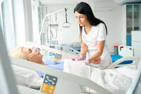 Téléchargez les photos : L'infirmière mesure la pression artérielle d'un patient après l'opération, le personnel médical porte des gants de protection - en image libre de droit