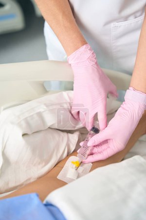 Foto de Enfermera hace una inyección en una vena de los pacientes con una jeringa grande, el personal médico con guantes de protección - Imagen libre de derechos