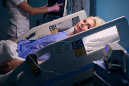 Foto de La mujer en recuperación se encuentra en la sala de recuperación, el personal médico monitorea su condición utilizando equipos modernos - Imagen libre de derechos