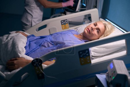 Foto de Mujer bonita se encuentra en la sala de recuperación, el personal médico monitorea su condición utilizando equipos modernos - Imagen libre de derechos