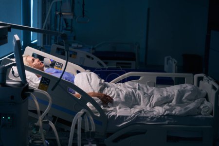 Photo for Lady is resting after surgery in the intensive care unit, she is connected to medical devices - Royalty Free Image