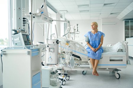 Photo for Patient is sitting on a bed in the intensive care unit, she is connected to support and monitoring devices - Royalty Free Image