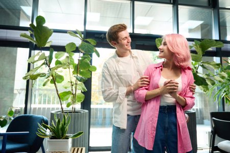 Téléchargez les photos : Les jeunes dans une chambre spacieuse avec des plantes vivantes, le gars étreint sa petite amie par les épaules - en image libre de droit