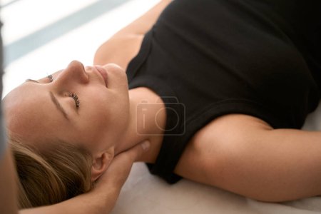 Téléchargez les photos : Femme lors d'une séance de thérapie manuelle repose sur une table de massage, la chiropraticienne travaille sur son cou - en image libre de droit