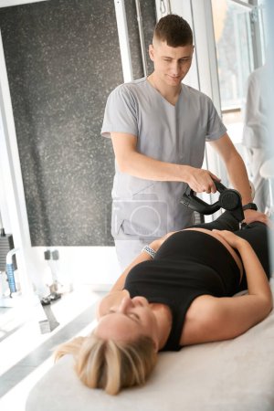 Photo for Specialist physiotherapist performs myostimulation on an expectant mother, using a special physiotherapeutic device - Royalty Free Image