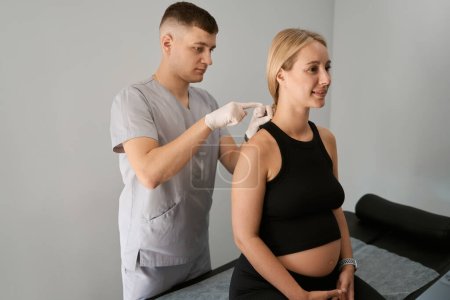 Téléchargez les photos : Réflexologue effectue une séance d'acupuncture pour une femme enceinte, le spécialiste travaille dans des gants de protection - en image libre de droit