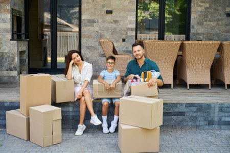 Photo for Family is moving to a new house, they have a lot of cardboard boxes with things - Royalty Free Image