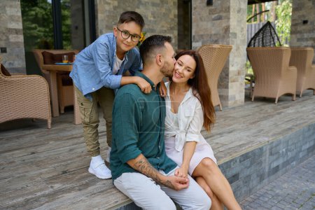 Téléchargez les photos : Sourire garçon câlins heureux parents, papa embrasse maman - en image libre de droit
