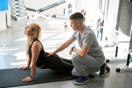 Photo for Physiotherapist instructor looks after an expectant mother in a health center, the gym has modern equipment - Royalty Free Image