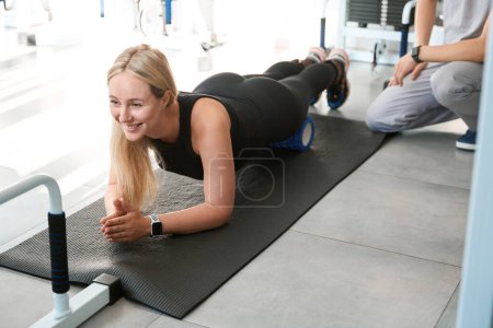Photo for Male physiotherapist controls the exercises of a pregnant blonde woman in the gym, a special device is used for exercises - Royalty Free Image