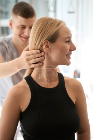 Photo for Male chiropractor works with a charming client in a wellness center, there is a lot of sunlight indoors - Royalty Free Image
