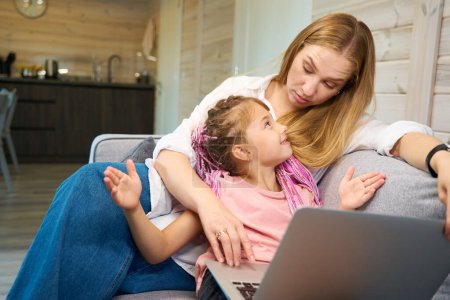 Photo for Dissatisfied mother looking at her daughter who cant cope with hard homework doing task on laptop, distant learning problems, bad marks - Royalty Free Image