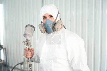 Foto de Retrato de pintor técnico en ropa protectora y con respirador sosteniendo pistola en la mano - Imagen libre de derechos