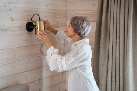 Photo for Pretty lady with lilac hair repairs a lamp herself, indoors eco-design - Royalty Free Image