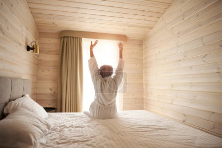 Foto de Mujer delgada se sienta en la cama en el dormitorio, se estira dulcemente - Imagen libre de derechos