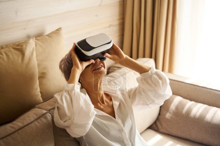 Foto de Joyful lady es apasionada por un juego virtual moderno, ella está usando gafas de realidad virtual - Imagen libre de derechos