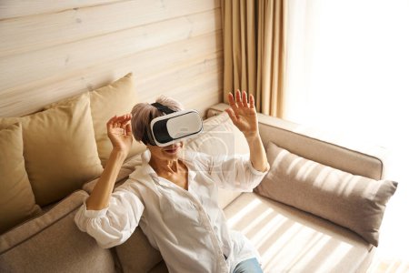Téléchargez les photos : Femme âgée est passionnée par un jeu virtuel, elle joue avec des lunettes spéciales - en image libre de droit