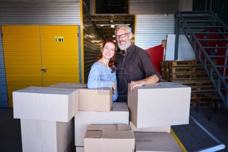 Téléchargez les photos : Les conjoints se tiennent près des boîtes avec des choses, un couple marié est dans un entrepôt - en image libre de droit