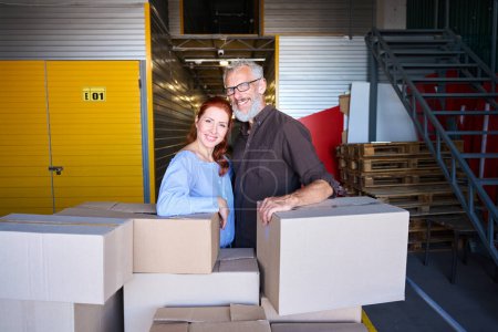 Téléchargez les photos : Un homme et une femme se tiennent près de boîtes avec des choses, un couple marié est dans un entrepôt - en image libre de droit