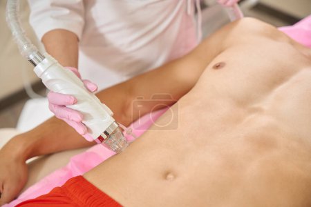 Foto de Doctor hace elevación de RF a un hombre joven, un especialista trabaja en el área abdominal - Imagen libre de derechos