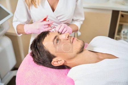 Photo for Man receives beauty injections in a cosmetology clinic, the doctor uses a thin needle - Royalty Free Image