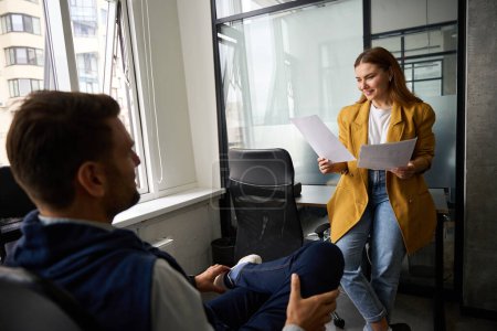 Photo for Woman in a yellow jacket communicates with a colleague in the office, people are working with documents - Royalty Free Image