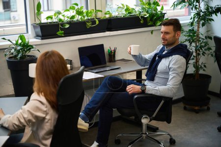 Téléchargez les photos : Les employés de bureau communiquent pendant une pause café, ils sont situés dans un bureau confortable - en image libre de droit