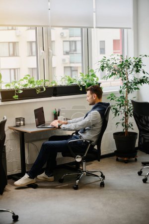 Foto de El hombre trabaja en una oficina cómoda y luminosa, usa una computadora portátil - Imagen libre de derechos