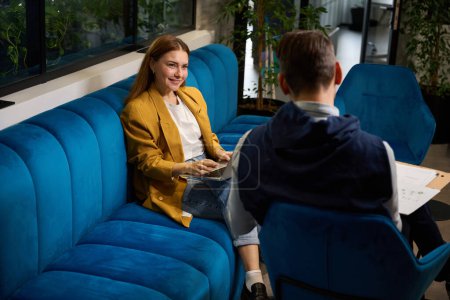 Téléchargez les photos : Homme et femme sont assis avec des documents de travail sur un confortable canapé bleu - en image libre de droit