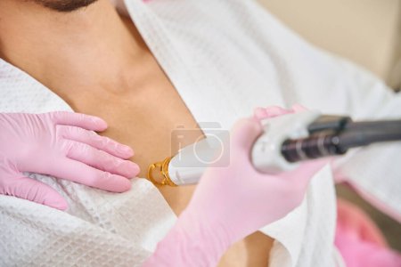 Photo for Specialist conducts a session of laser breast hair removal for a young client, a woman works in protective gloves - Royalty Free Image
