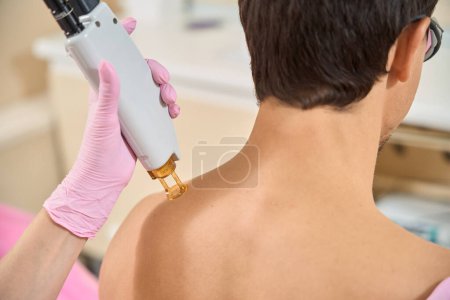 Photo for Male at a shoulder laser hair removal session, a professional uses modern equipment - Royalty Free Image